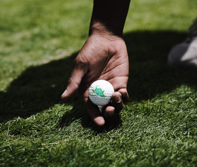 Hand reaching for a golf ball on a tee with a custom logo print