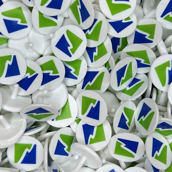 White custom golf ball markers featuring a blue and green geometric logo