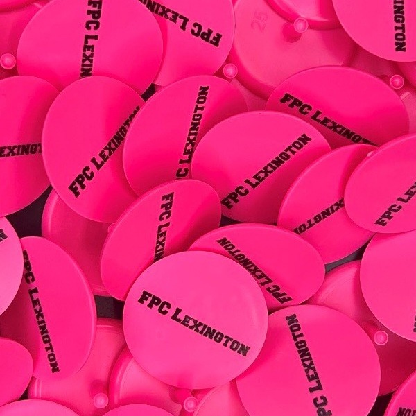 Hot pink custom golf ball markers printed with black lettering