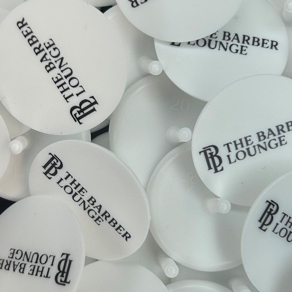 White branded golf markers printed with a black barbershop logo
