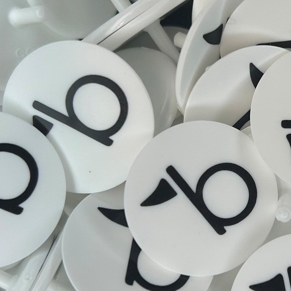 White custom ball markers printed with a large black letter logo