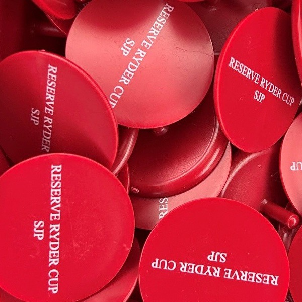 Red custom golf markers printed in white for a golf tournament