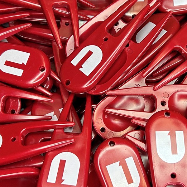 Red custom divot tools featuring bold white logo printing
