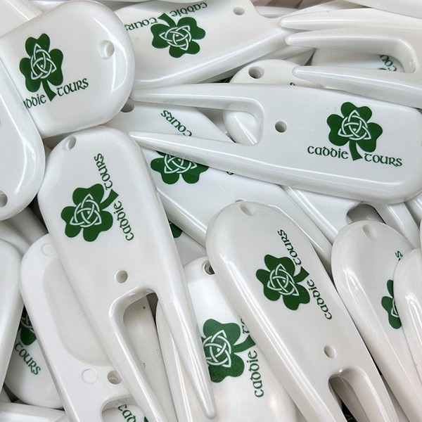 White custom divot tools printed with a green golf club logo