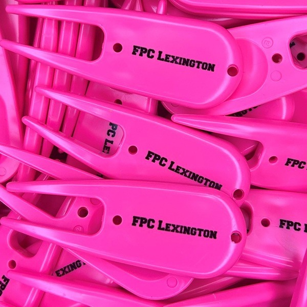 Hot pink personalized divot tools printed with black lettering