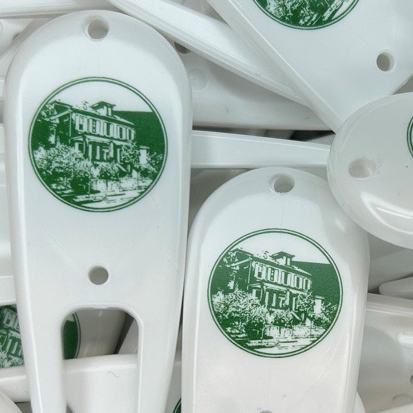 White custom divot repair tools printed with green company logo
