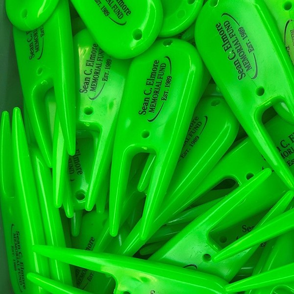 Green branded divot tools printed with a memorial fund logo