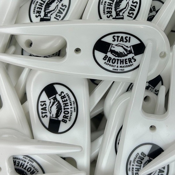 White custom divot tools printed with a black handshake logo