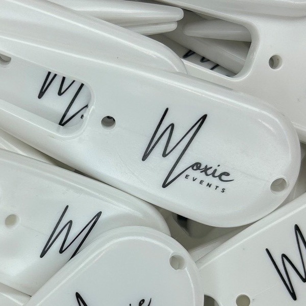 White branded divot tools printed with a black script logo