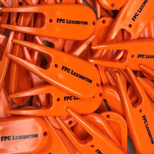 Orange custom divot tools printed with black company lettering