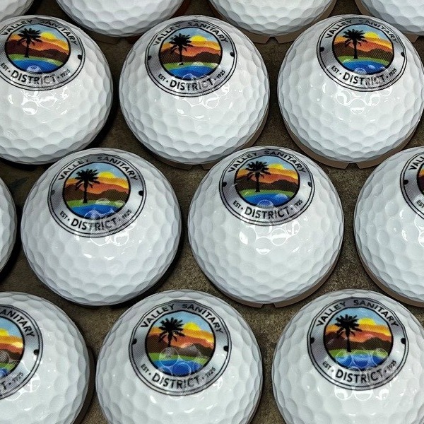 White custom golf balls printed with a full-color sunset district logo