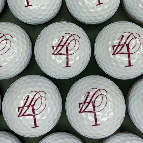 White personalized golf balls printed with a maroon anniversary number design