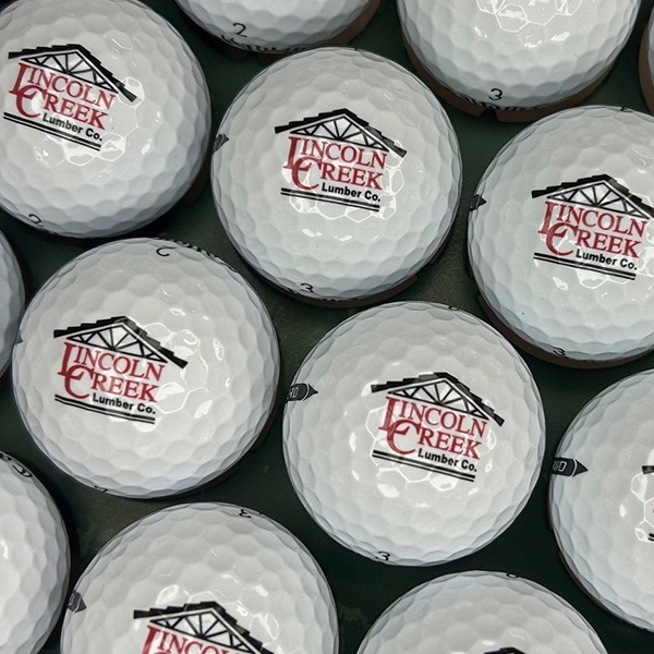 White custom golf balls printed with a red and black lumber company logo