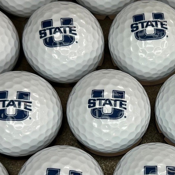 White custom golf balls printed with a navy university logo