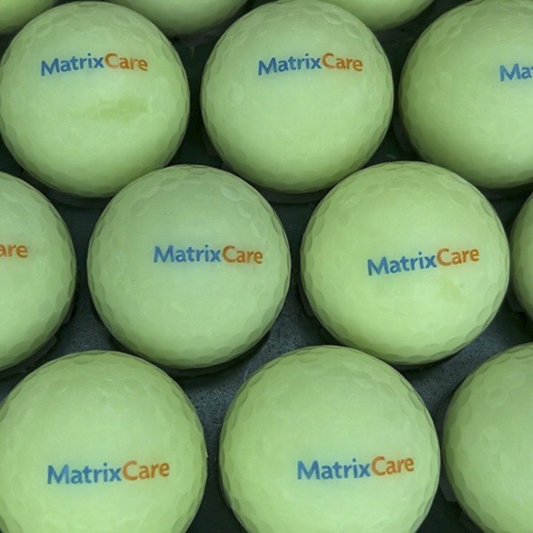 Pale yellow custom golf balls printed with a blue and orange logo