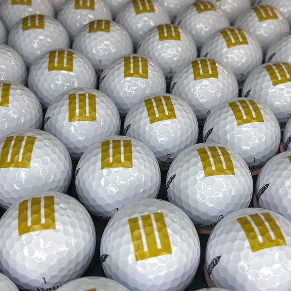 Custom logo golf balls featuring a simple gold geometric design